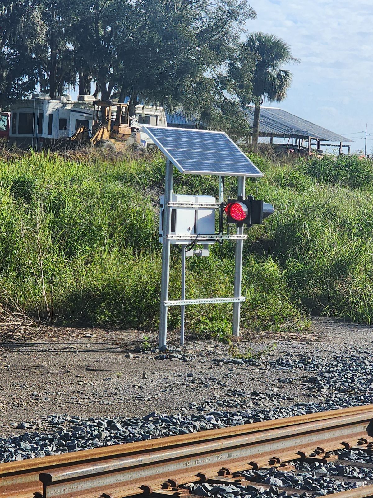 Solar-powered railroad switch position indicator displaying a red signal beside the track